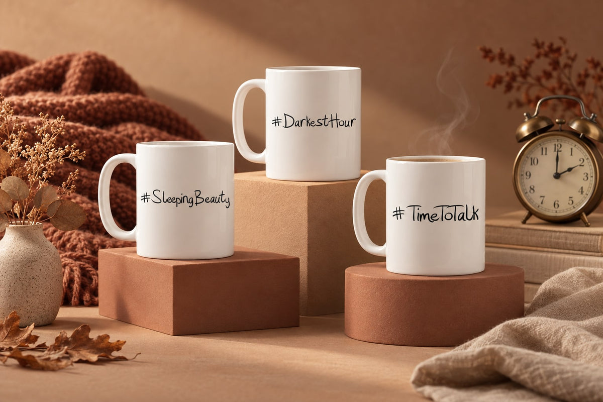 Mugs on a wooden bedside table next to an old wind-up alarm clock and a glowing lamp, with soft early morning light coming through the window of a cosy bedroom.